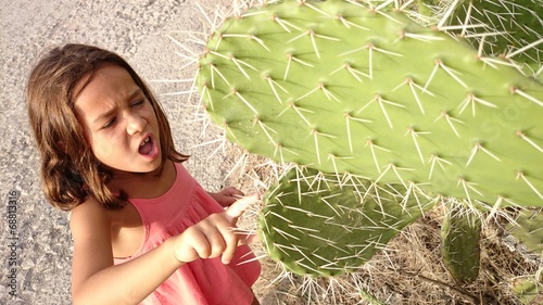 Niña pinchándose con cactus photo