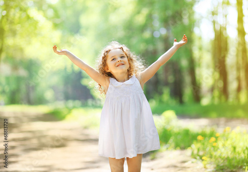 Foto Charming little girl enjoying summer sunny day, raises his hands