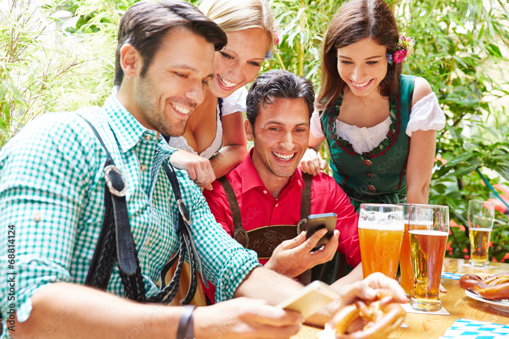 Obraz premium Freunde im Biergarten schauen auf Smartphones