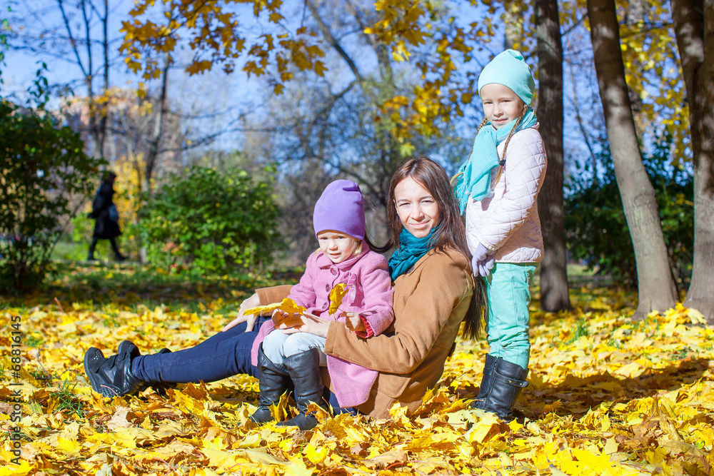 Little girls and young mother in autumn park
