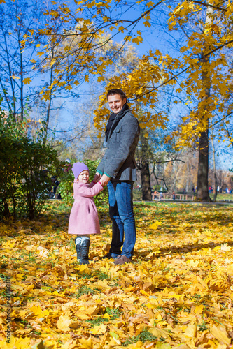 Adorable little girl with happy father outdoor in autumn park