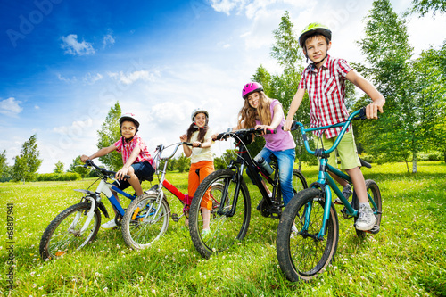 Happy kids in colorful bike helmets holding bikes
