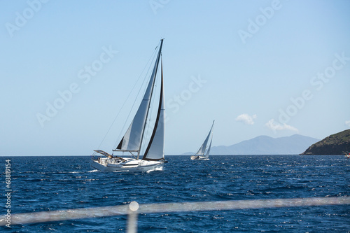 Sailing ship yachts with white sails in the sea.