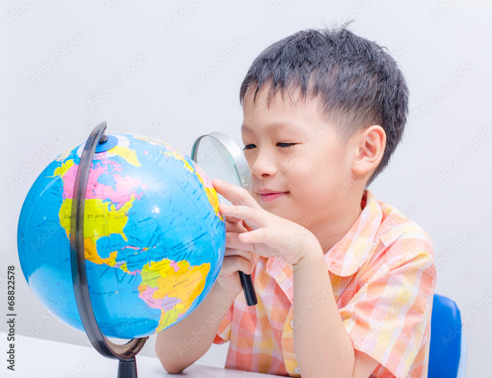 Asian boy looking at a globe by magnifying glass Asian boy looking at a globe by magnifying glass