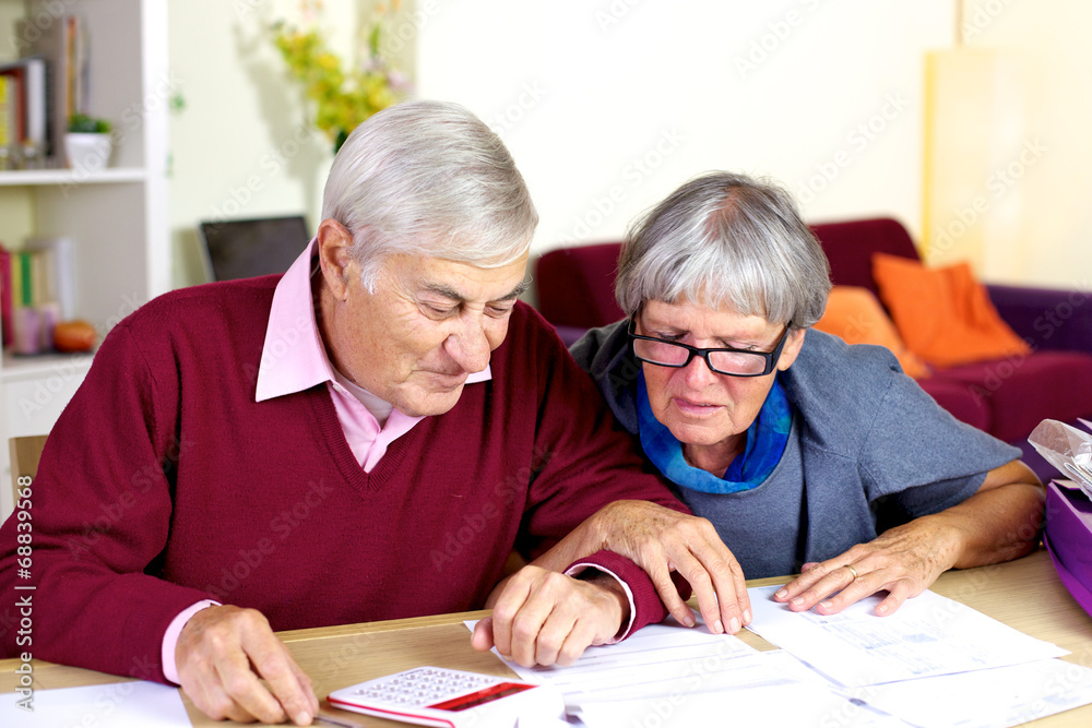 Happy senior couple at home calculating debt Happy senior couple at home calculating debt