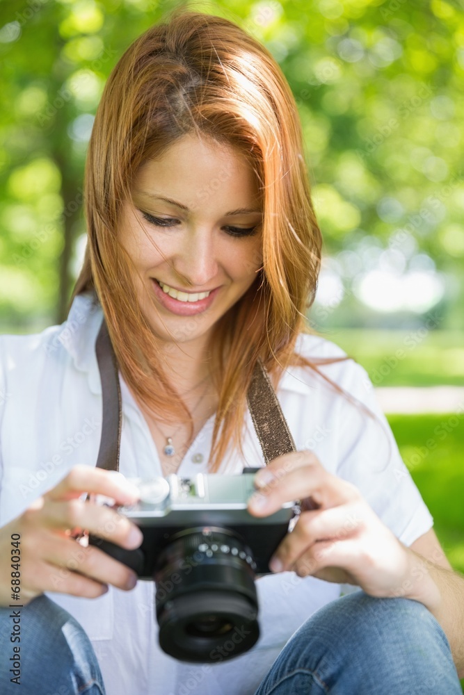 Pretty redhead looking at her camera in the park Pretty redhead looking at her camera in the park