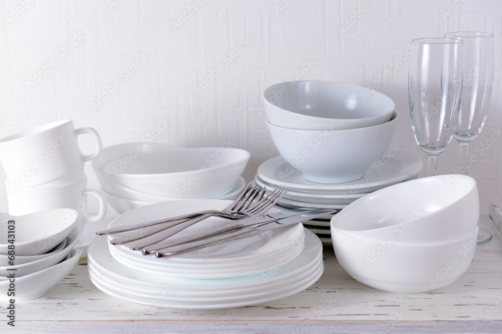 Set of white dishes on table on light background Set of white dishes on table on light background