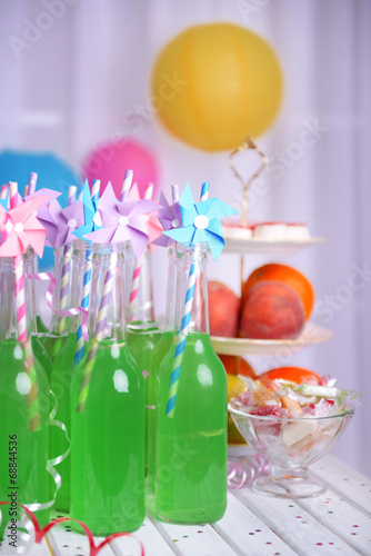 Bottles of drink with straw and fruits on decorative background