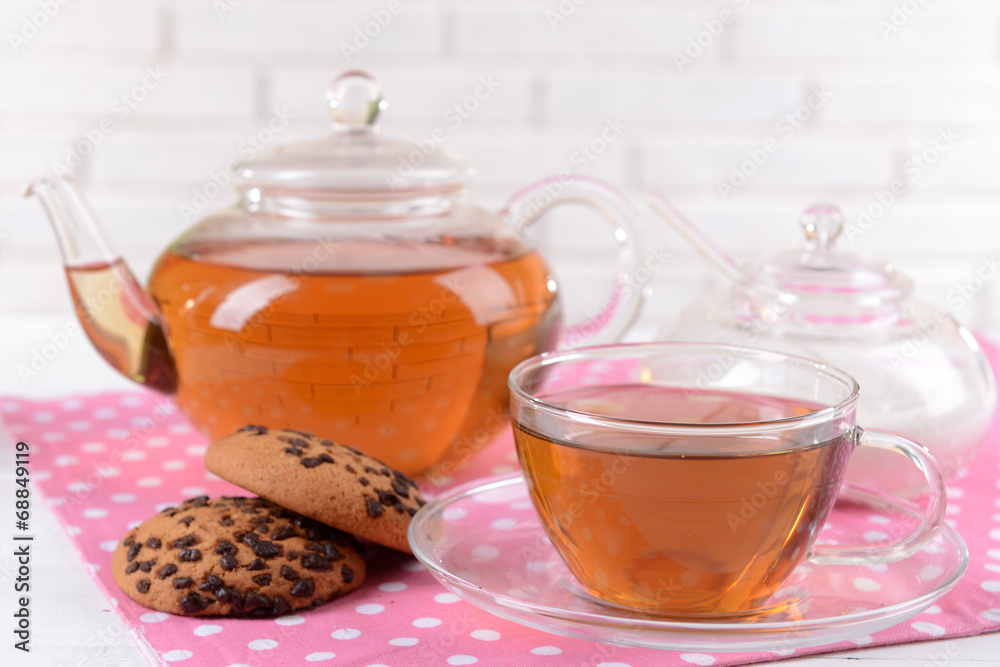 Teapot and cup of tea on table on brick wall background Teapot and cup of tea on table on brick wall background