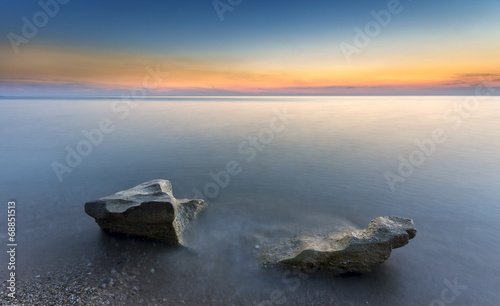 astonishing radiant sunset and tworocks in the silky water photo