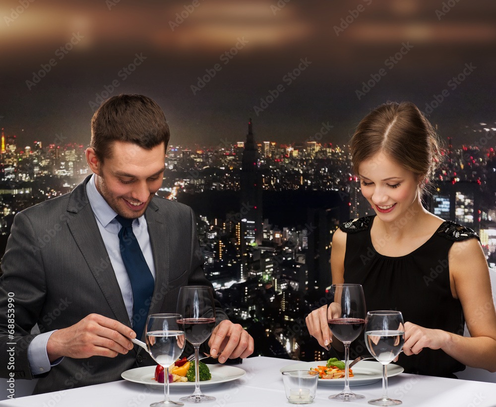 smiling couple eating main course at restaurant