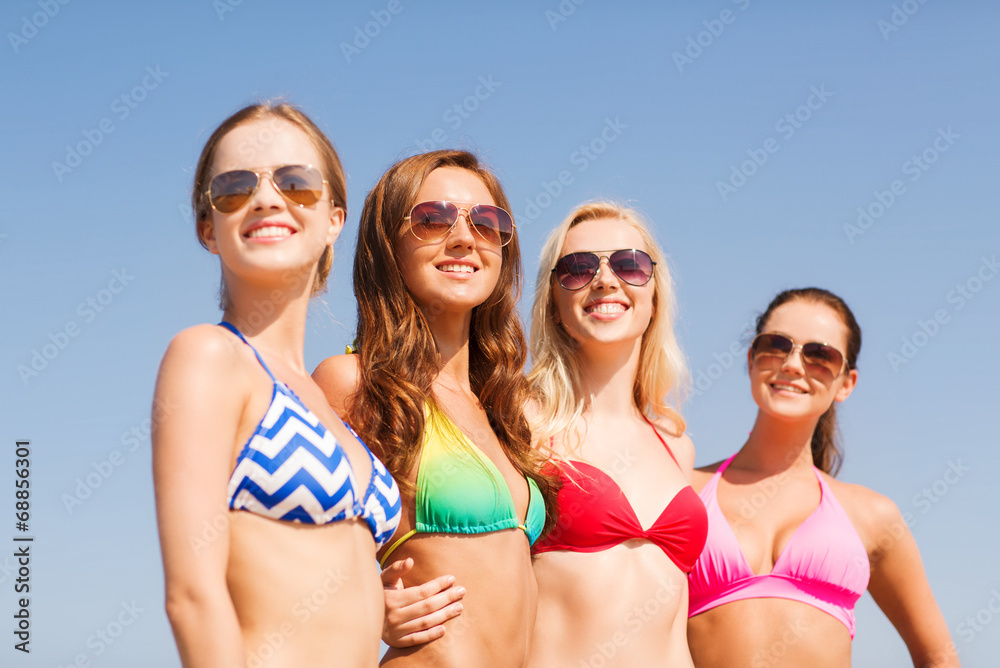 group of smiling young women on beach