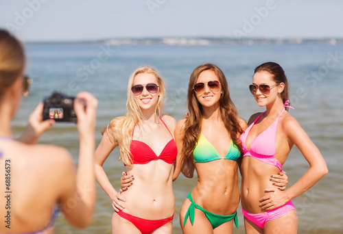 group of smiling women photographing on beach