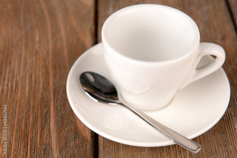 Empty cup with tea spoon on wooden background