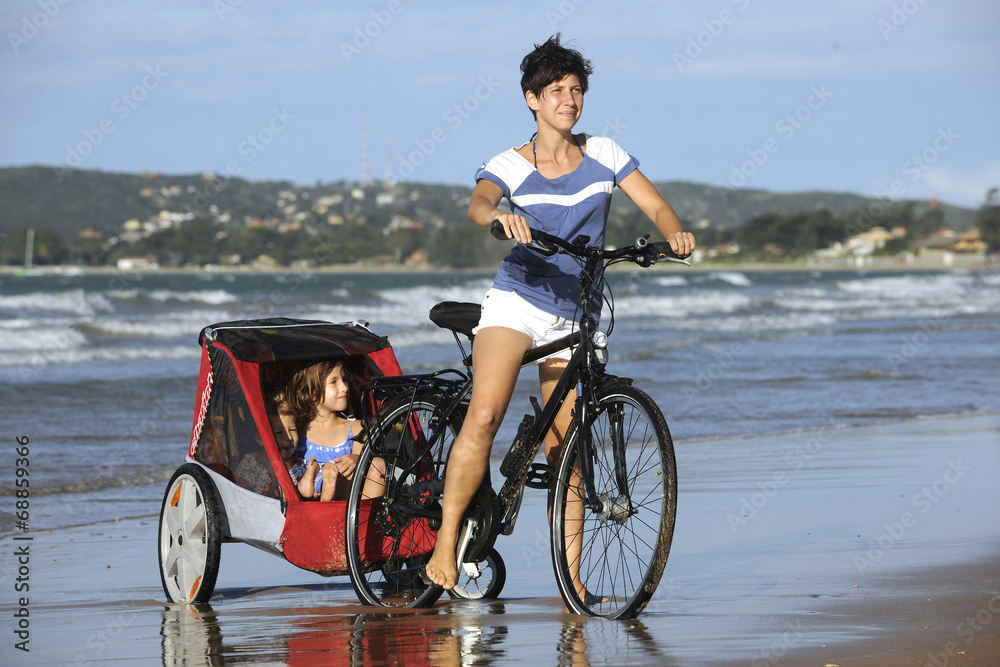 Mother and daughters riding a bike on the beach.