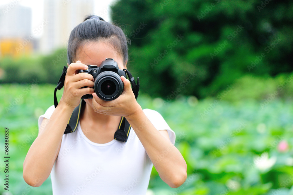 young woman photographer taking photo of blooming lotus at park 