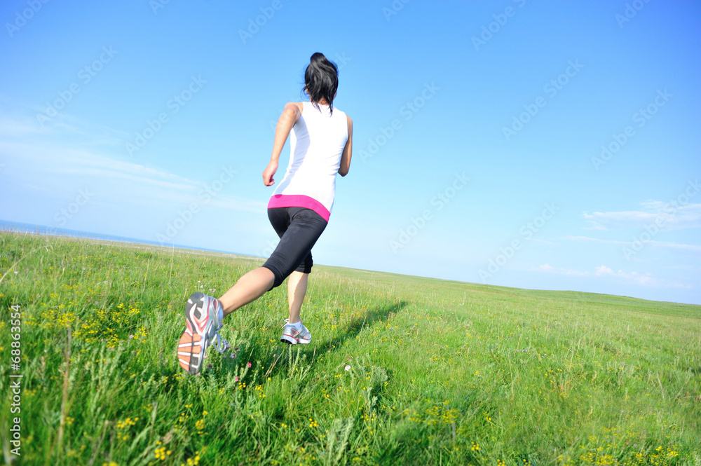 Runner athlete legs running on grass seaside Runner athlete legs running on grass seaside
