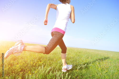 Runner athlete legs running on sunrise grass seaside