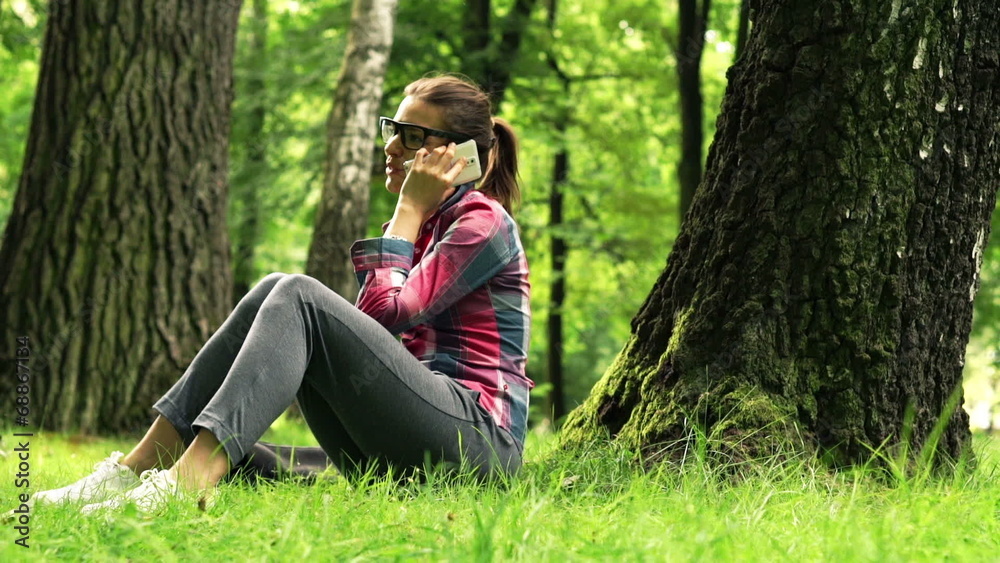 Young woman talking on cellphone in the park Young woman talking on cellphone in the park