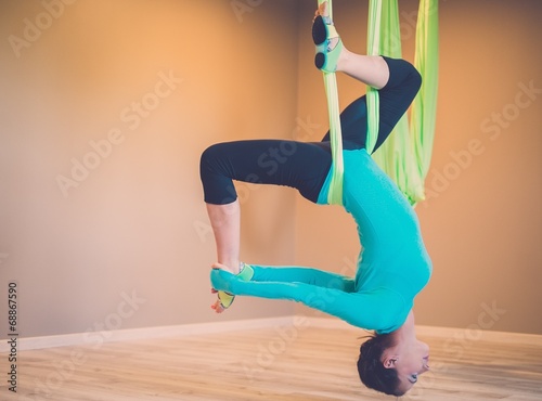 Young woman performing aerial yoga exercise photo