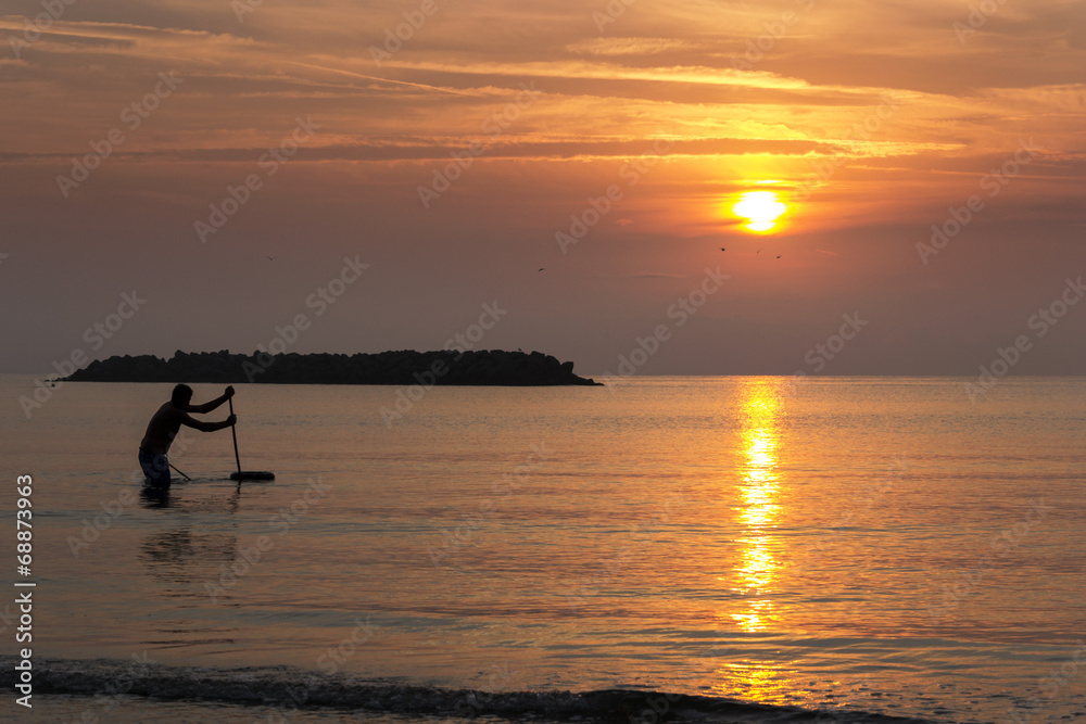 Fishing man in the sea during the sunrise
