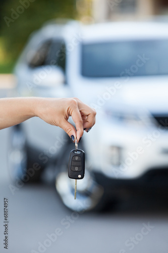 Suv defocused on background and woman hand with ignition key