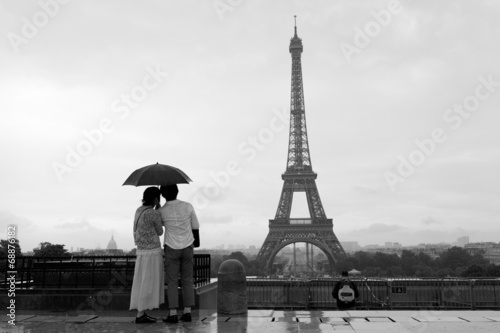 Streets of Paris with Eiffel Tower in rain, with couple admiring
