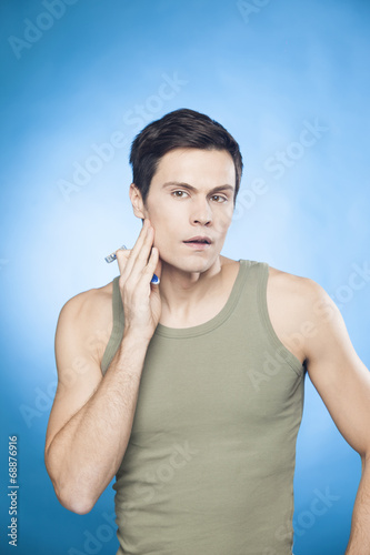 Handsome man in green tank top shaving 