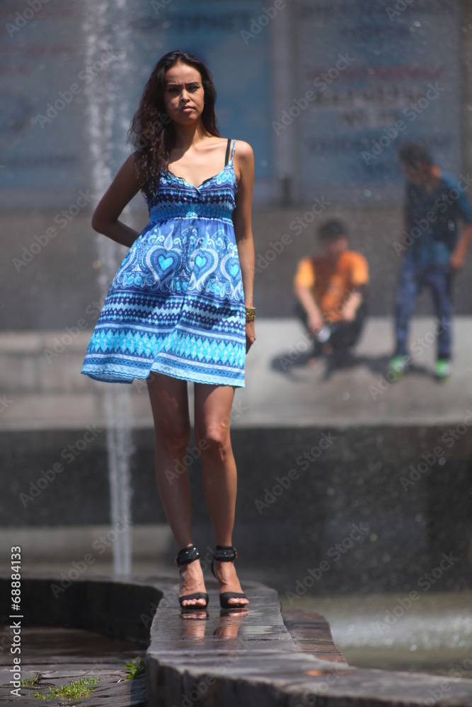 Naklejka premium Fashionable woman in blue dress at the fountain