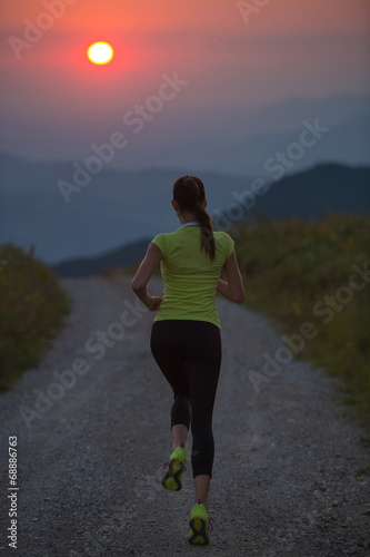 woman running on a mountain road at summer sunset © Samo Trebizan