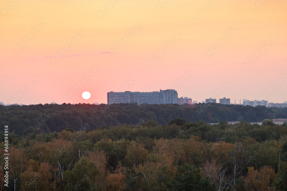 sun during red sunrise over houses and urban park