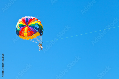 фотографія people parascending on parachute in blue sky