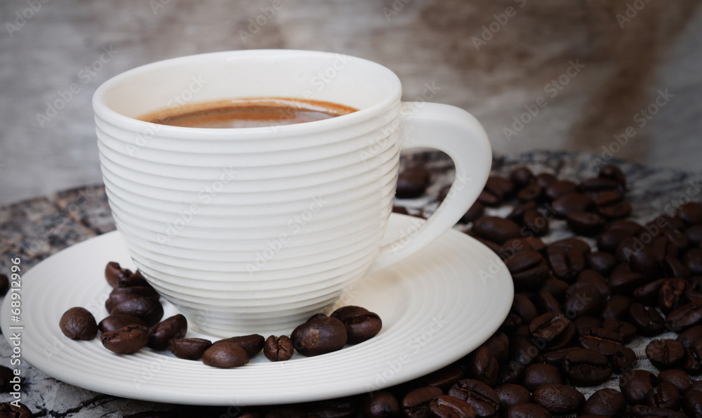 Fototapeta premium White cup in coffee beans, closeup