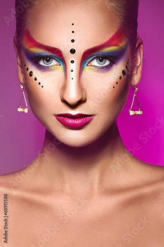 Portrait of fashion model with multicolor make up on purple back