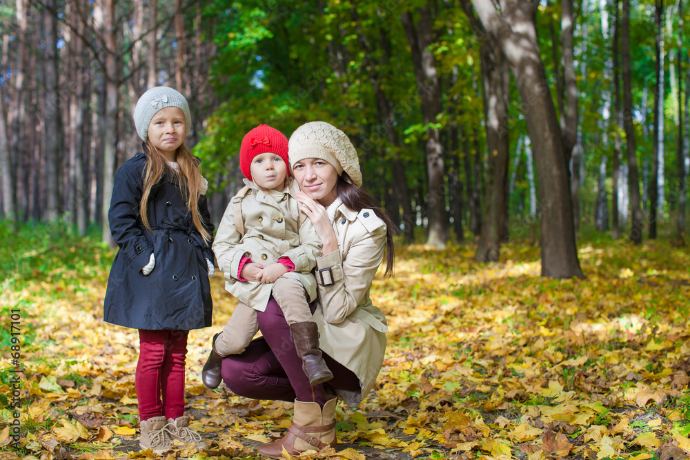 Little cute girls and young mother in autumn park have fun Little cute girls and young mother in autumn park have fun
