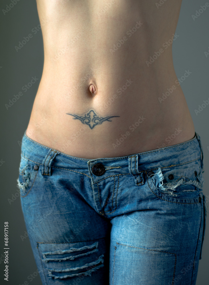 Flat female belly with tattoo in jeans Stock Photo | Adobe Stock