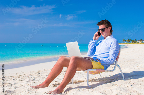 Young man working on laptop at tropical beach © travnikovstudio
