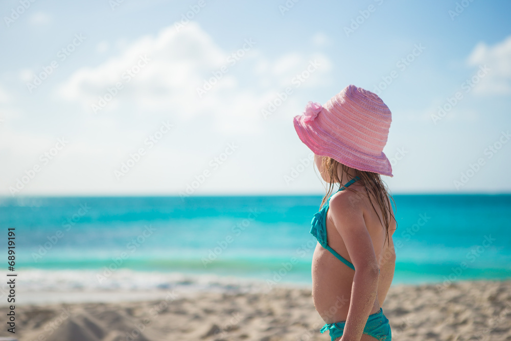 Adorable little girl in hat on beach during summer vacation