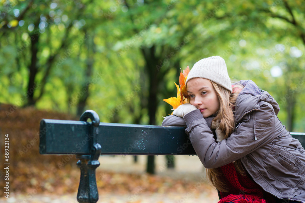 Girl sitting alone on the bench on a fall day