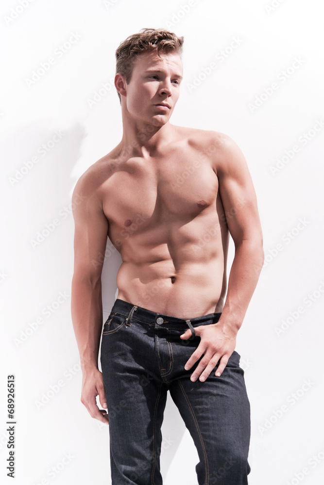 Male fitness model wearing blue jeans. Blonde hair. Against whit Male fitness model wearing blue jeans. Blonde hair. Against whit