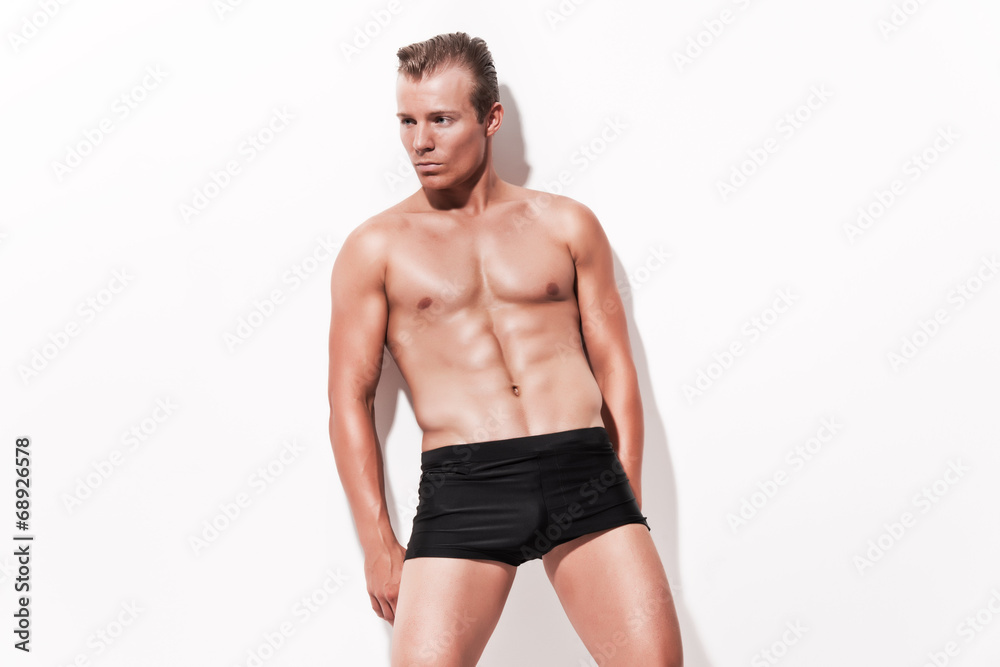 Male muscled underwear model wearing black shorts. Blonde hair.
