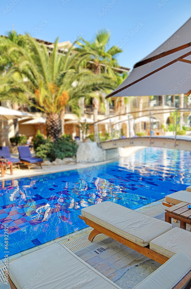 Fototapeta premium Deck chairs next to a swimming pool in an exotic location