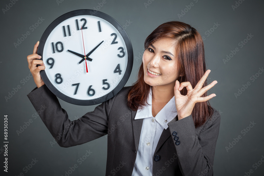 Asian businesswoman hold a clock show OK sign and smile Asian businesswoman hold a clock show OK sign and smile