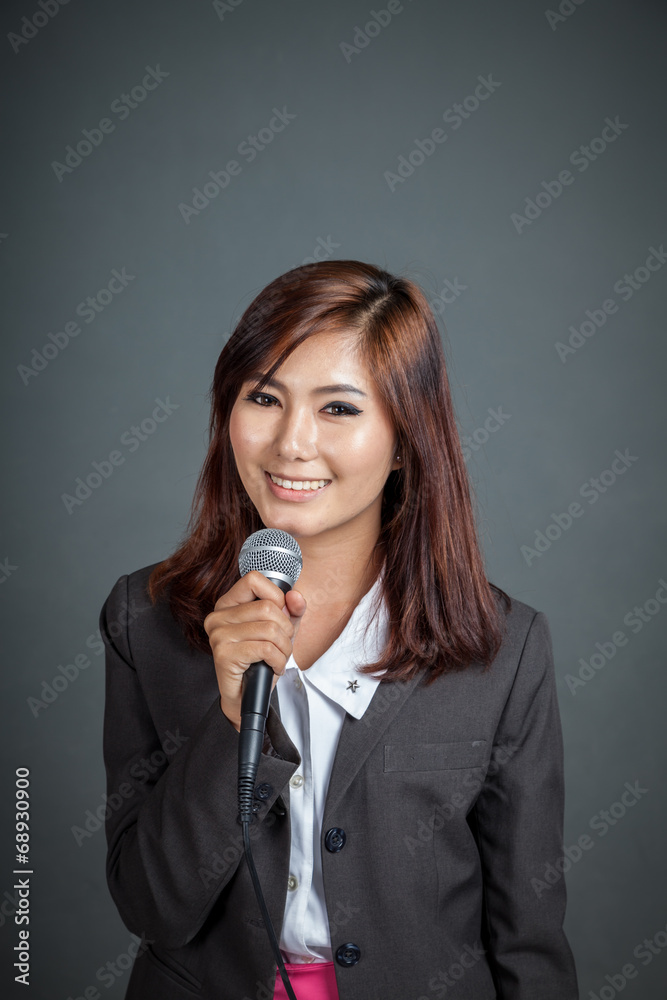 Asian business girl hold a microphone and smile Asian business girl hold a microphone and smile