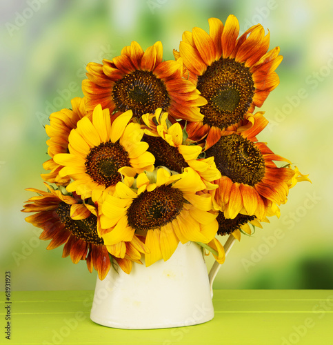 Fototapeta Naklejka Na Ścianę i Meble -  Beautiful sunflowers in pitcher on table on bright background