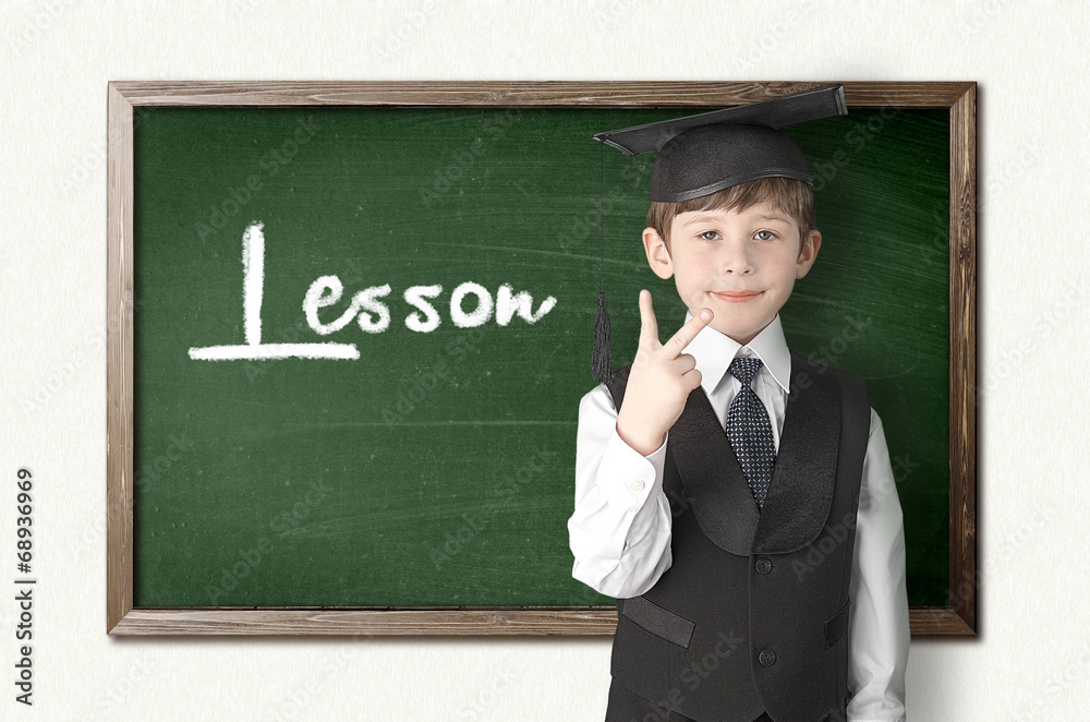 Cheerful little boy on blackboard. Looking at camera
