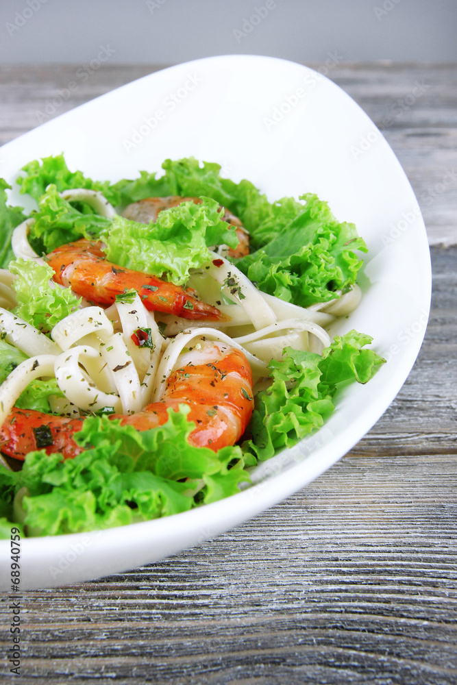 Fresh prawns with spaghetti, olives and lettuce in a white oval Fresh prawns with spaghetti, olives and lettuce in a white oval