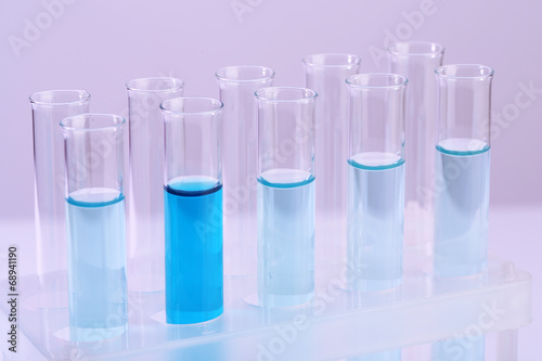 Test-tubes with blue liquid on lilac background