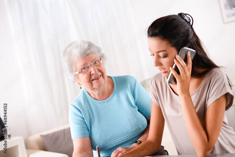 young woman helping old person for paperwork and telephone call young woman helping old person for paperwork and telephone call