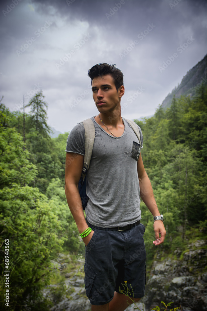 Handsome athletic young man with backpack in mountains